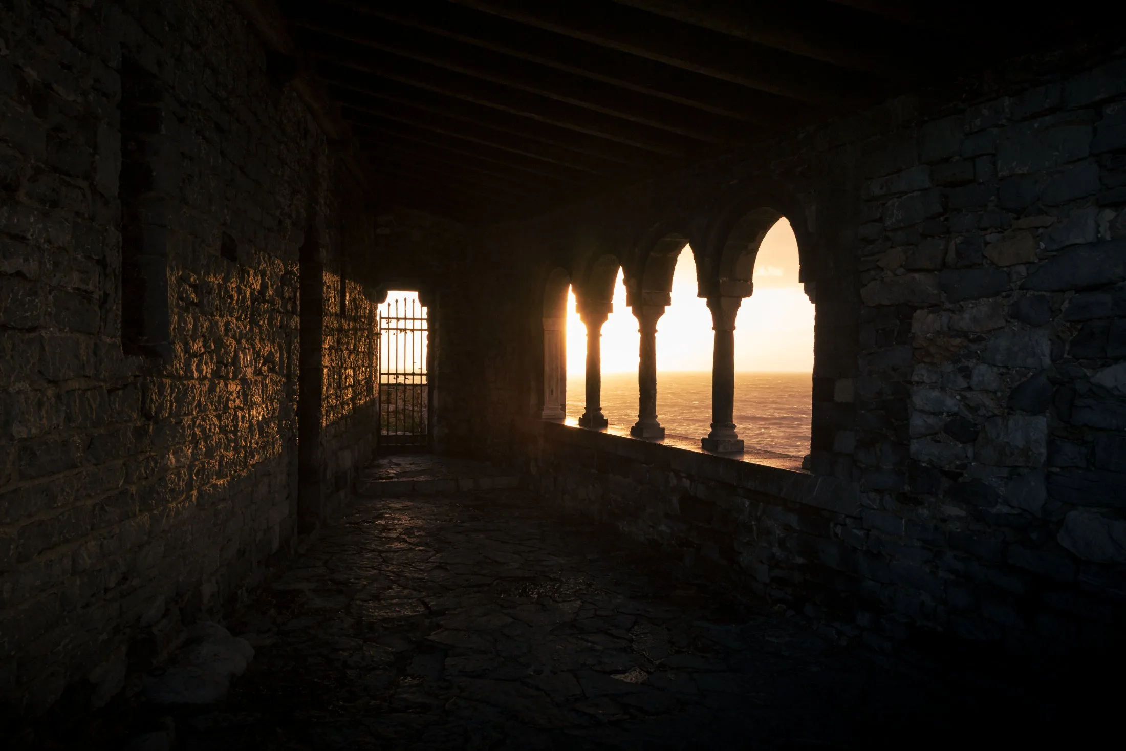 Corridoio in pietra con archi aperti sul tramonto