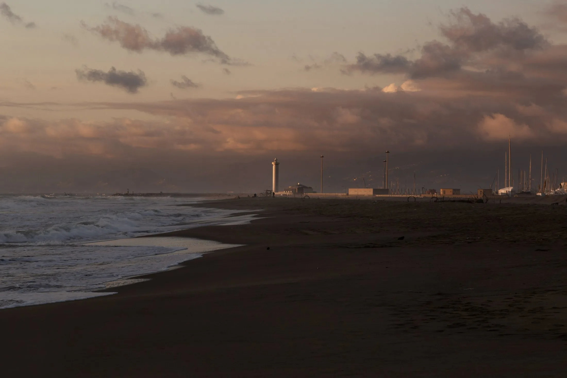 Spiaggia al tramonto con mare mosso e nuvole